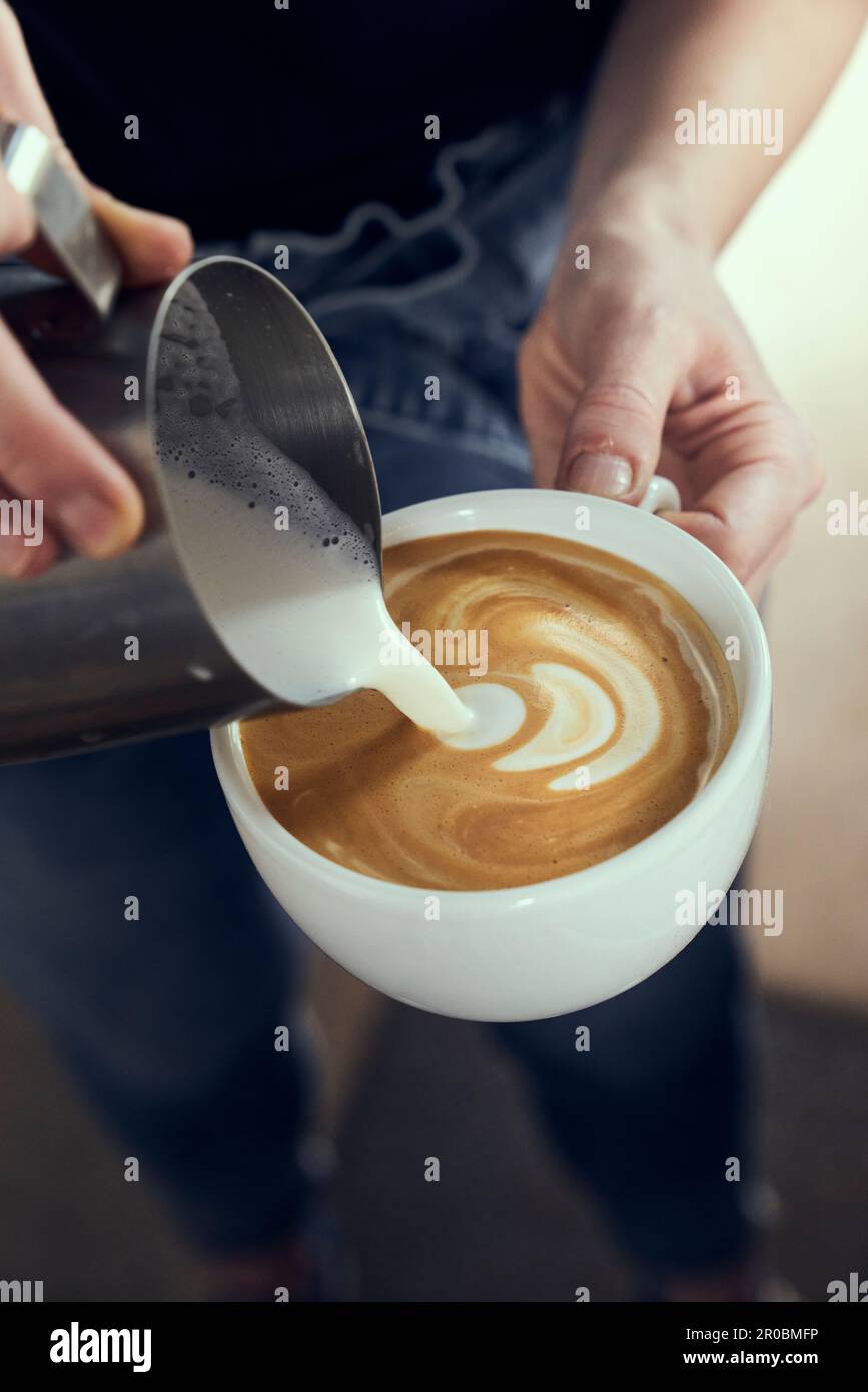 Latte Art étant versé à la main dans un latte frais dans une tasse blanche. Banque D'Images