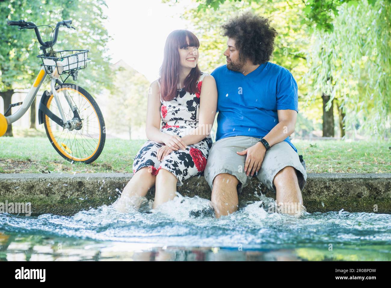 Couple heureux barbotant de l'eau à la rivière Eisbach Banque D'Images