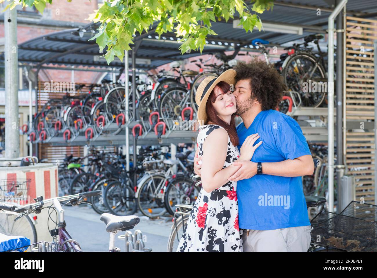un jeune couple s'embrasse par un parking à vélos Banque D'Images