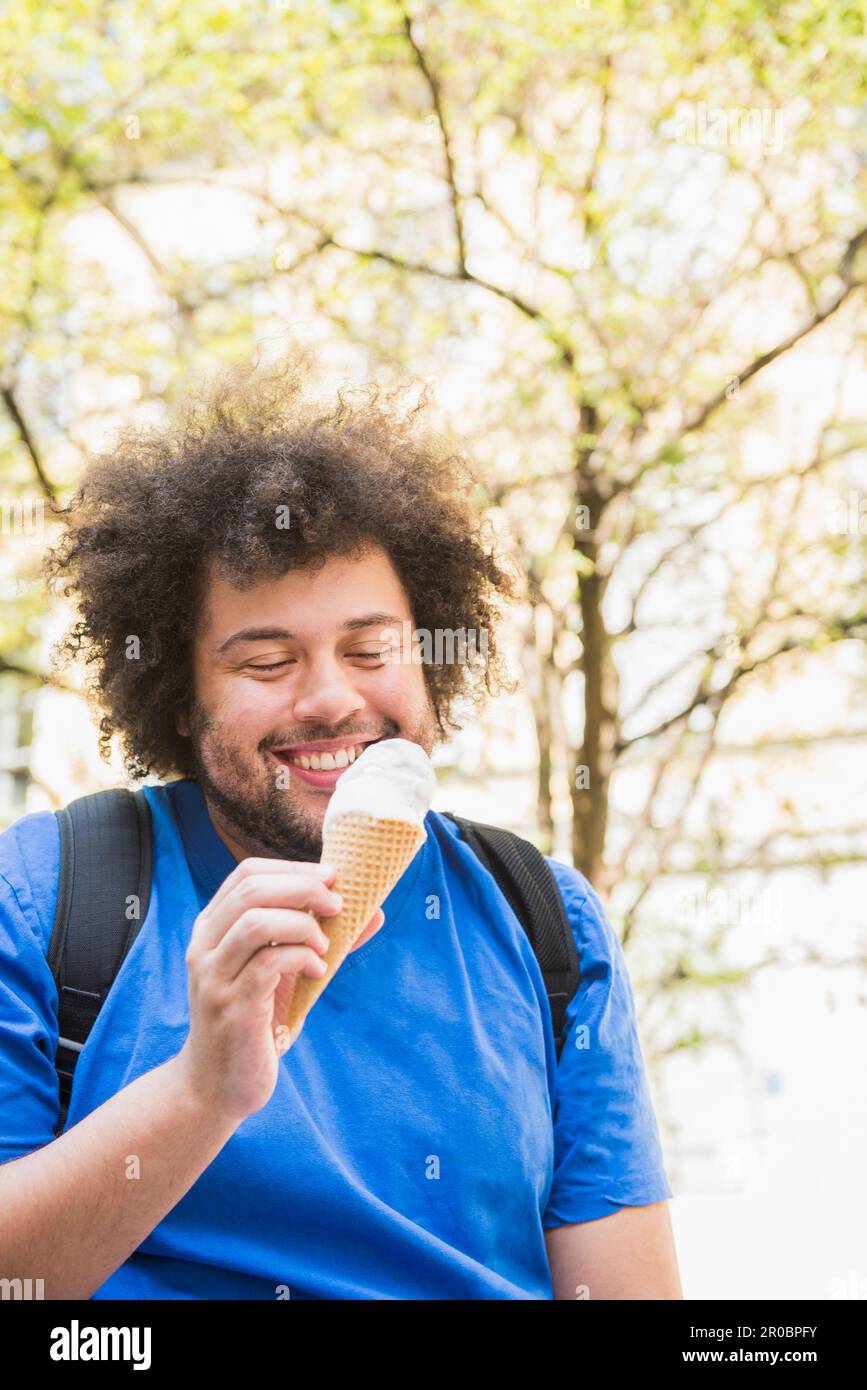 Joyeux jeune homme qui mange de la glace Banque D'Images