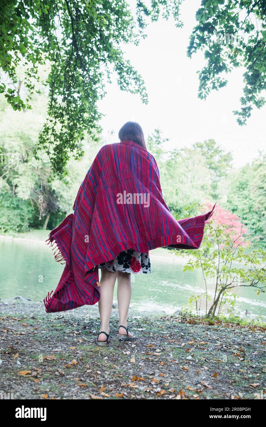 Femme enveloppée dans une couverture au bord du lac dans le jardin anglais, Munich, Allemagne Banque D'Images