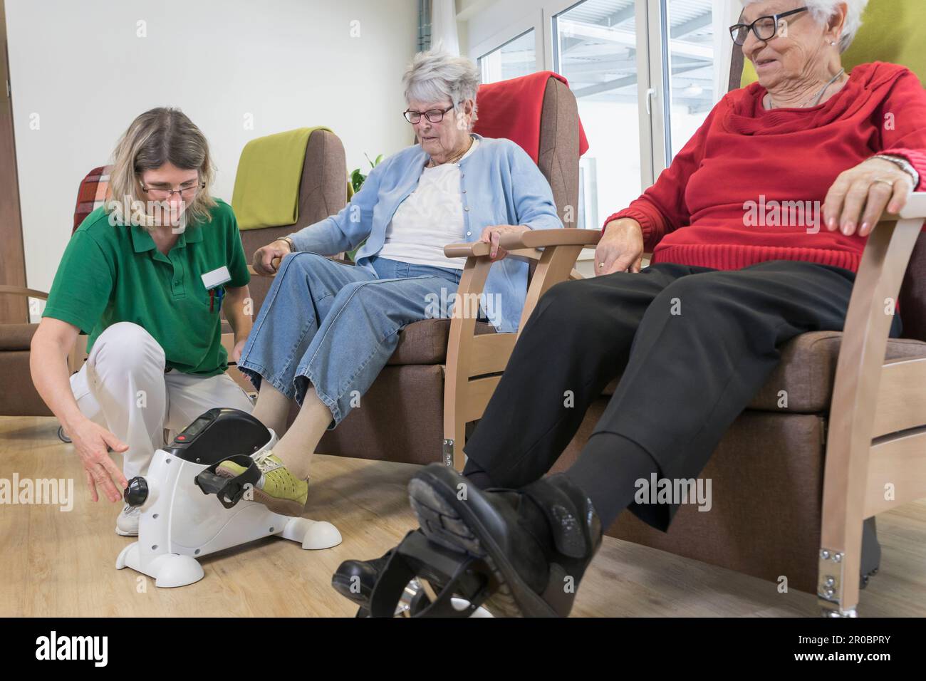 Infirmière aidant les femmes âgées faisant de l'exercice sur la mini pédale dans la maison de repos Banque D'Images