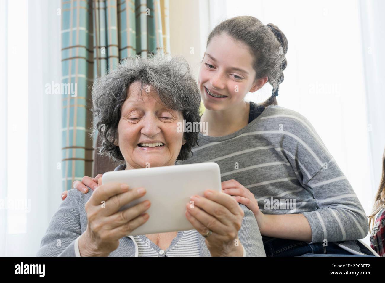 Femme âgée avec petite-fille utilisant une tablette numérique au repos à la maison Banque D'Images