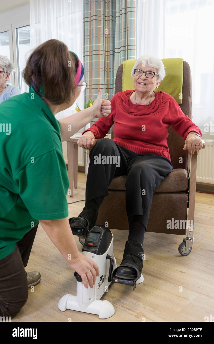 Infirmière avec une femme âgée s'exerçant sur un vélo d'exercice dans une maison de repos Banque D'Images