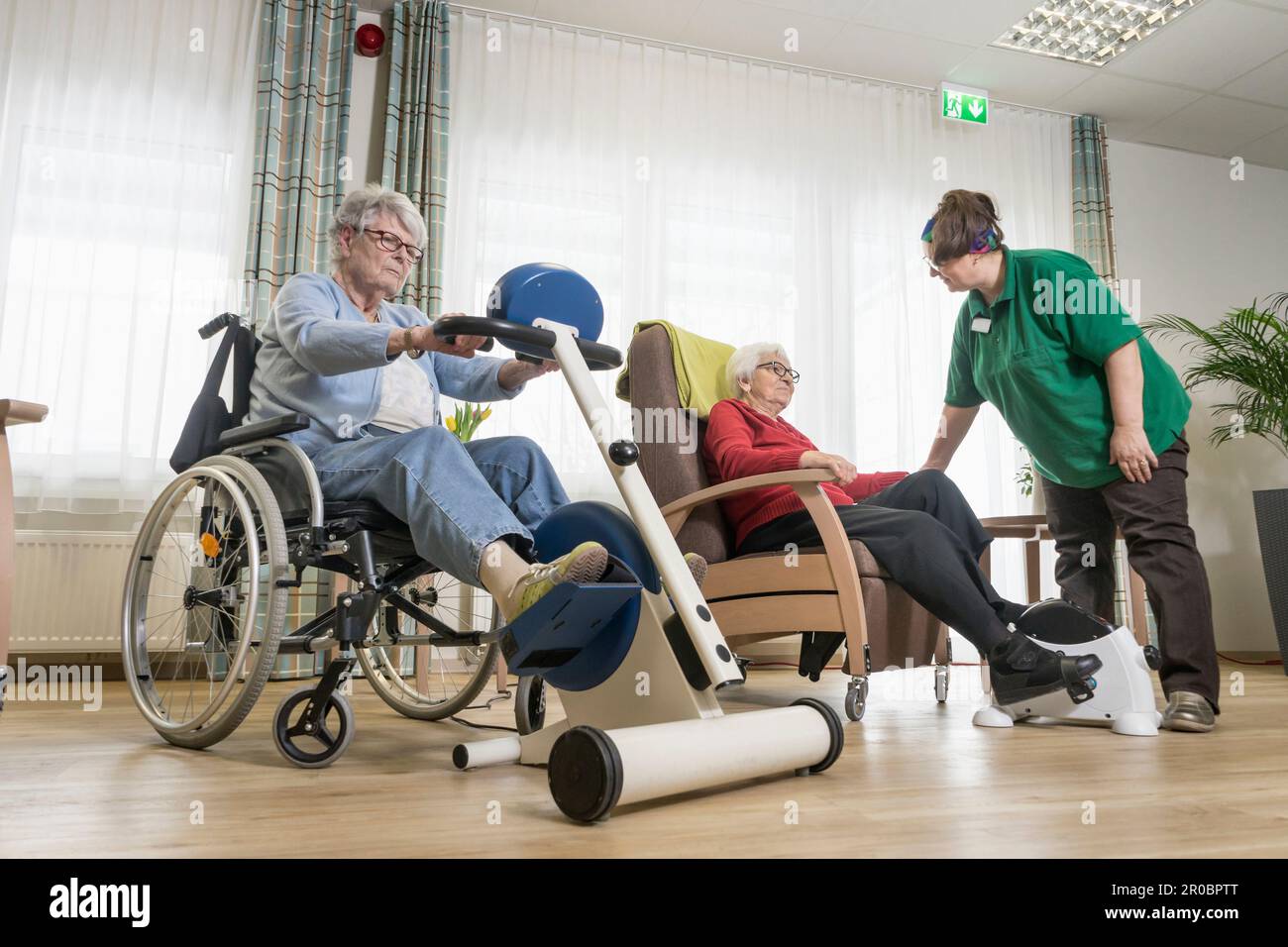 Infirmière avec des femmes âgées s'exerçant sur un vélo d'exercice dans la maison de repos Banque D'Images
