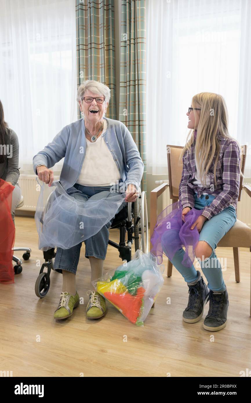 Les filles et la femme âgée faisant de l'exercice de sport doux avec le tissu dans la maison de repos Banque D'Images