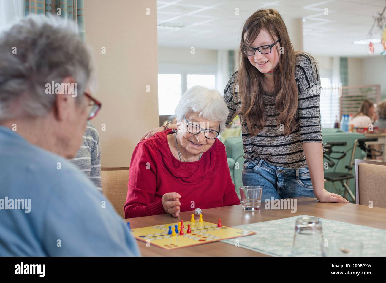 Filles jouant au ludo jeu de société avec des femmes âgées dans la maison de repos Banque D'Images
