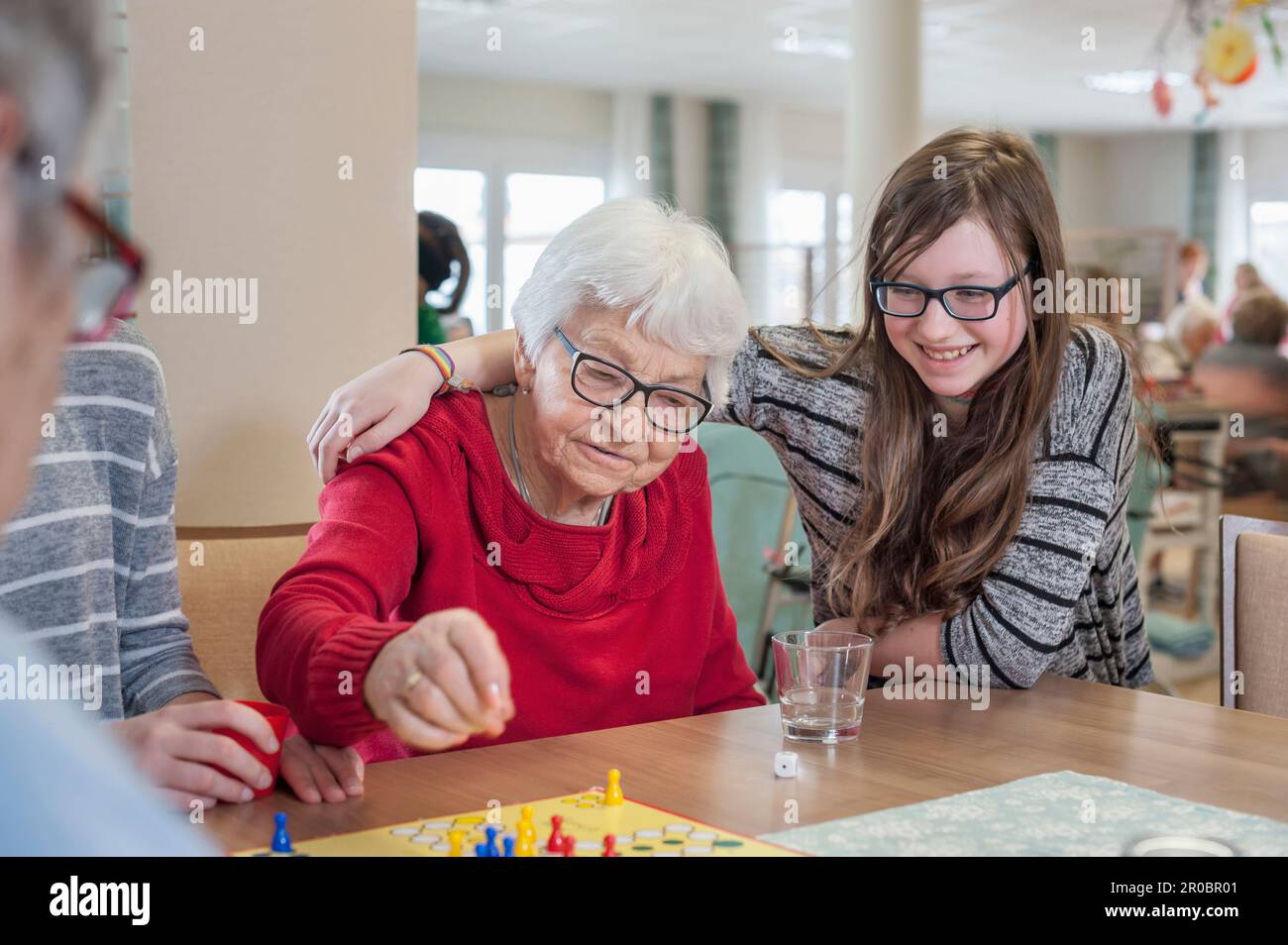 Filles jouant au ludo jeu de société avec des femmes âgées dans la maison de repos Banque D'Images