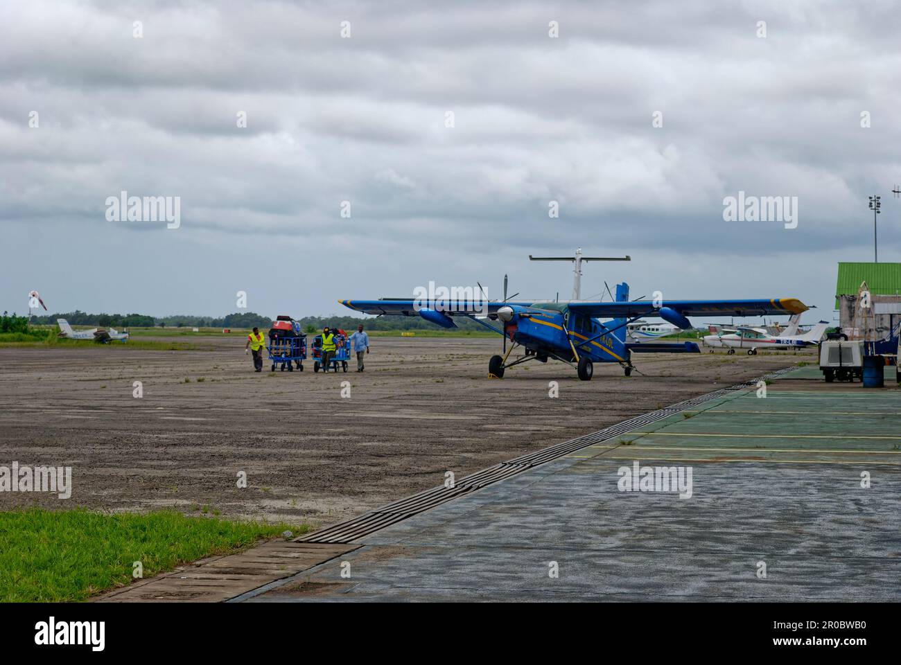 Les employés des aéroports qui se mettent à transporter des chariots à bagages jusqu'au terminal de l'aéroport de Port-Gentil, dans le pays ouest-africain du Gabon, en train de dépérir la saison des pluie Banque D'Images