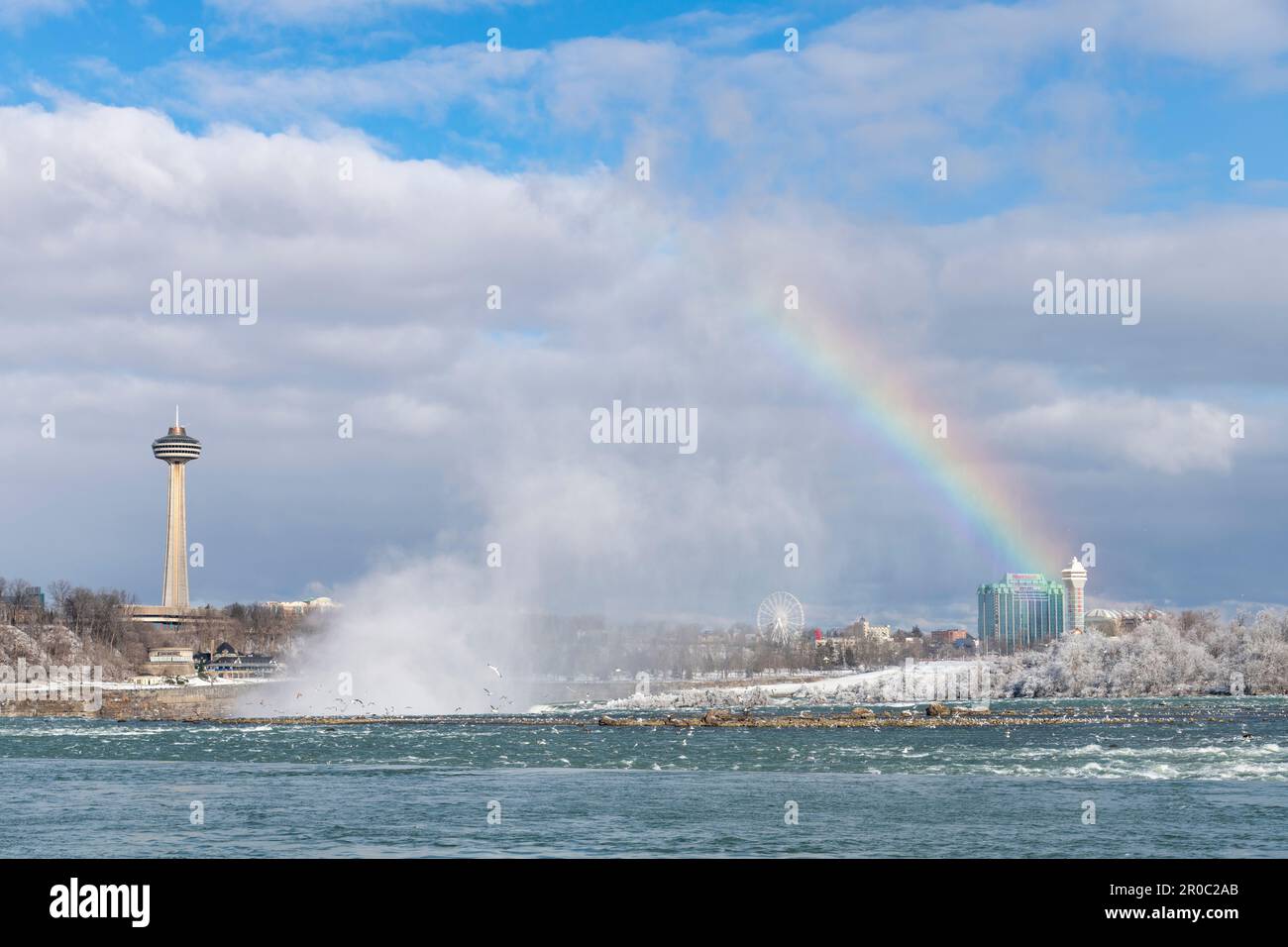 Niagara Falls, ON, Canada-février 2023; vue panoramique depuis les chutes du Niagara en amont en hiver avec pulvérisation d'eau et arc-en-ciel au-dessus des chutes et avec la SK Banque D'Images