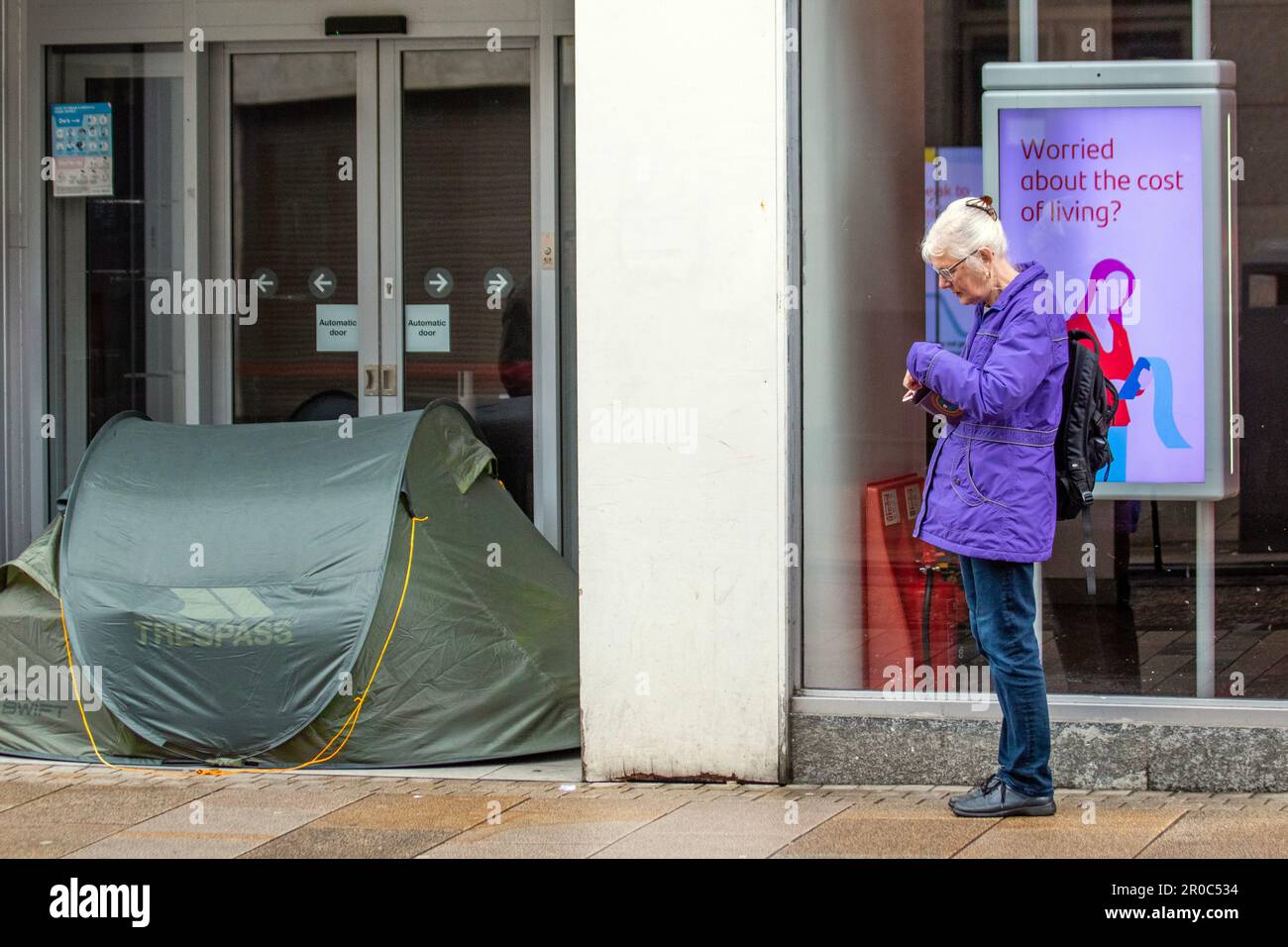 Le sommeil agitée, ayant érigé une tente dans la porte de SANTANDER Bank. Magasins, acheteurs magasiner sur une banque humide et venteuse lundi de vacances à Preston, Lancashire, Royaume-Uni crédit; MediaWorldImages/AlamyLiveNews Banque D'Images