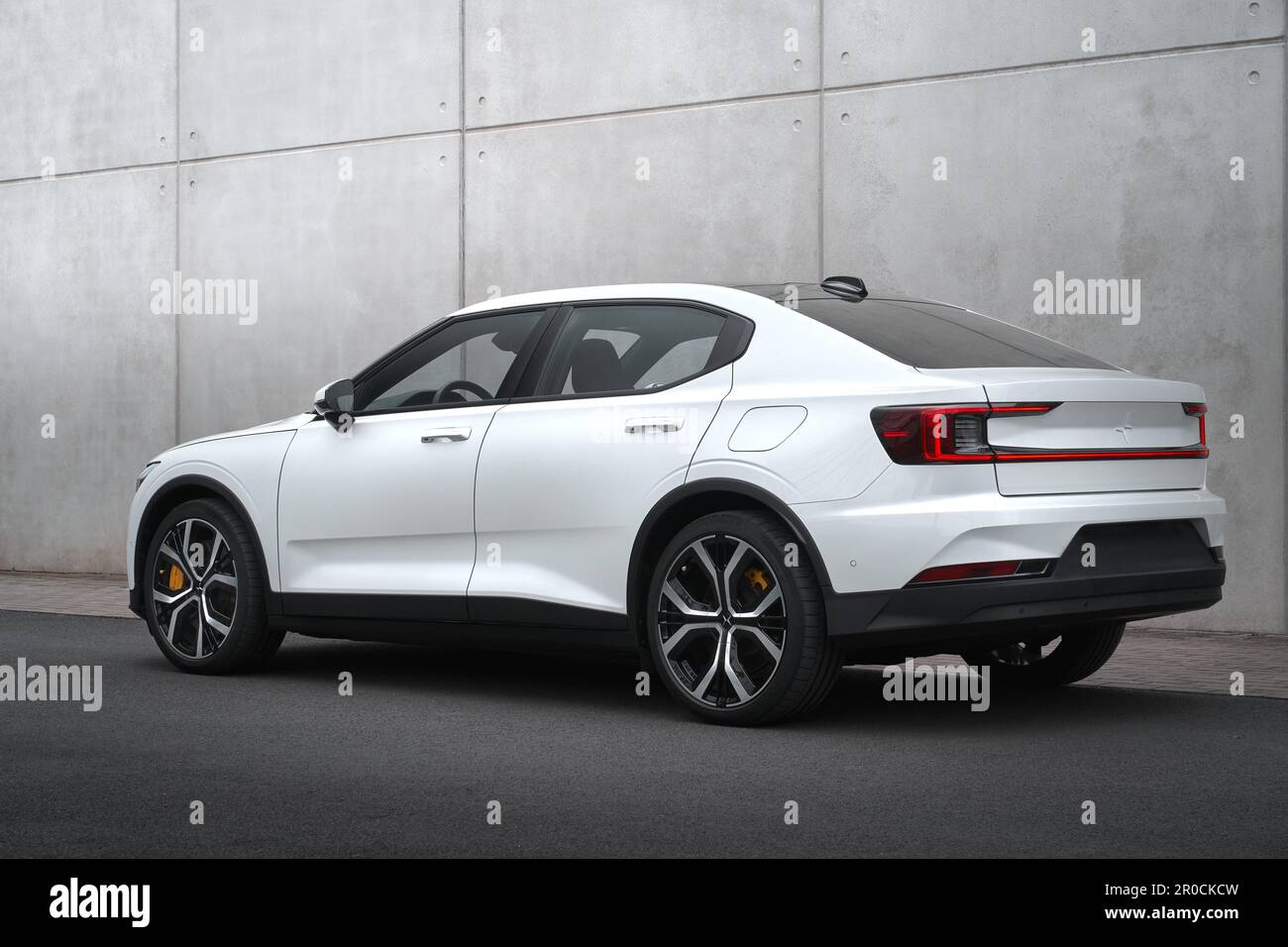 Un Polestar blanc 2 avec un pack performance devant un mur en béton léger. Banque D'Images