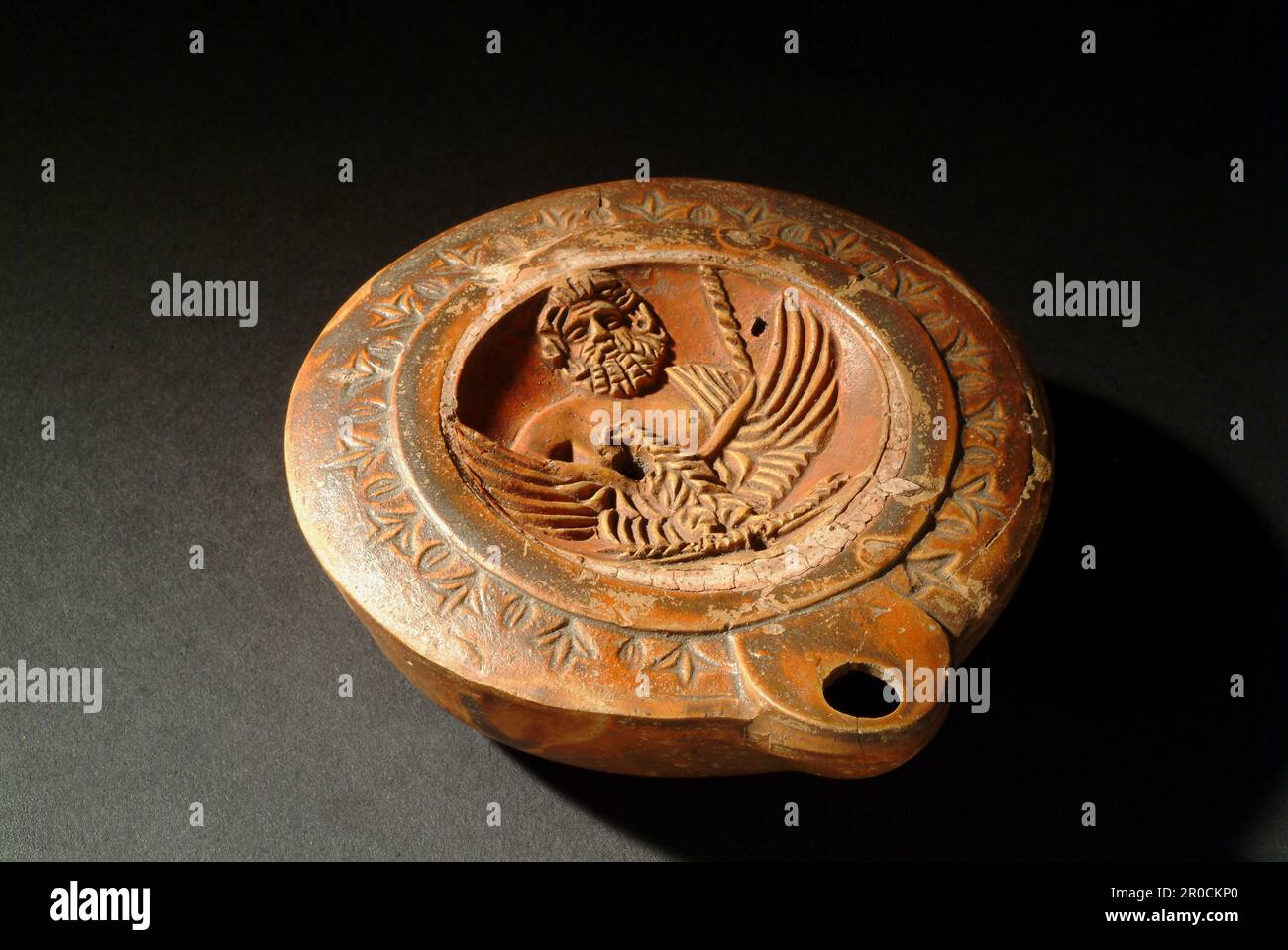 Lampe de poterie romaine. Décoré de buste de Zeus avec son aigle, ses griffes saisissant un boulon de tonnerre. Banque D'Images