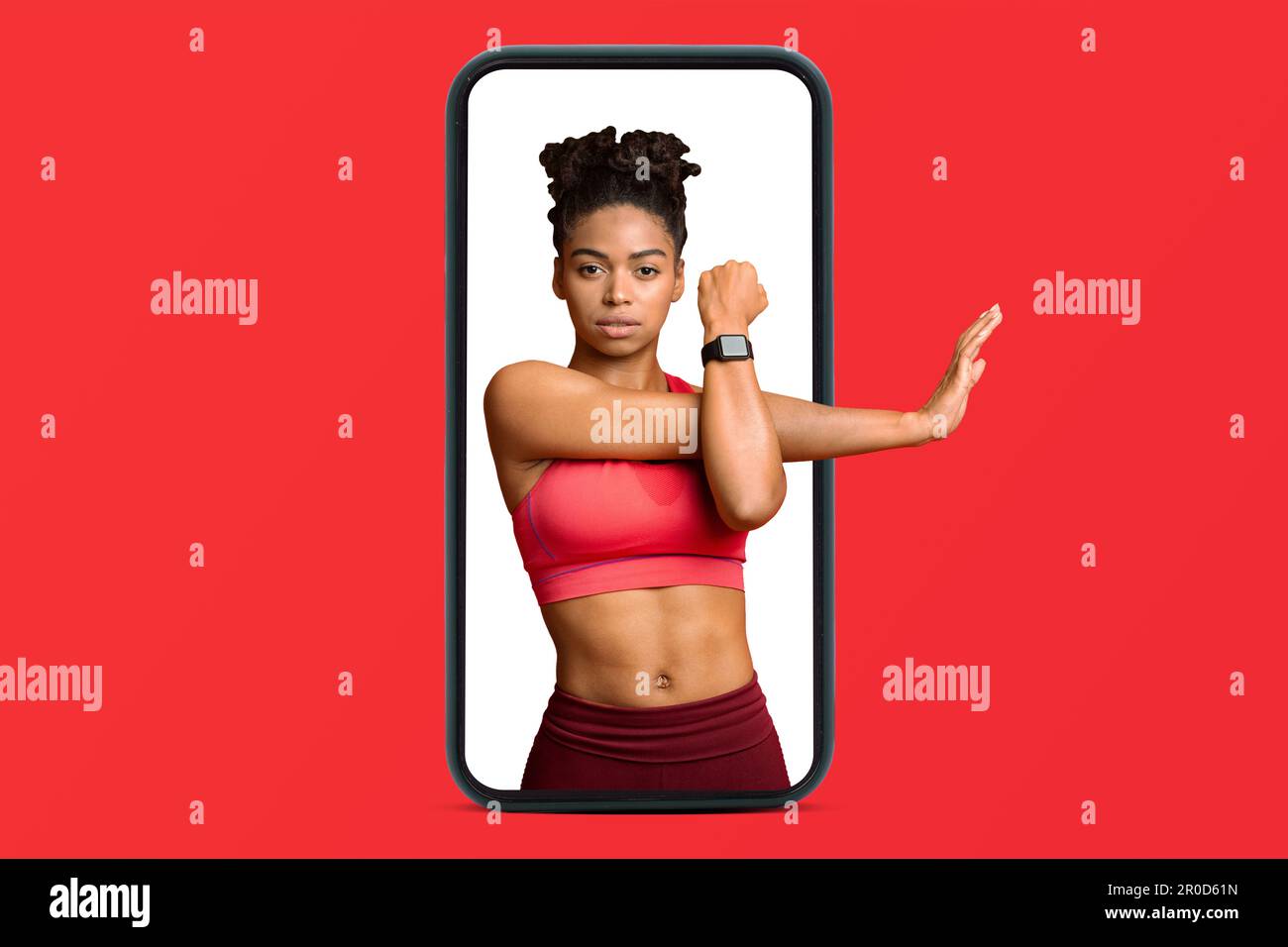 Confiante jeune afro-américaine mince dame dans sportswear faire des exercices d'étirement pour les mains sur smartphone Banque D'Images