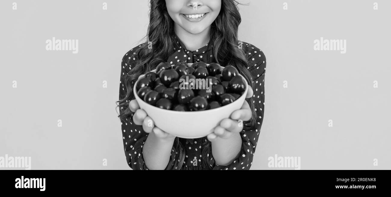 vue rognée et sélection de la mise au point du bol en cerisier dans les mains sur fond jaune Banque D'Images
