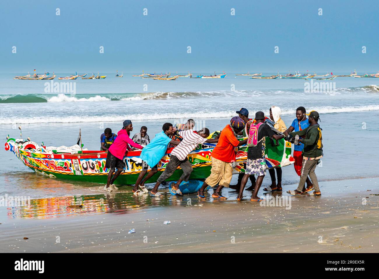 Hommes tirant bateau de pêche coloré, Cap Skirring, Casamance, Sénégal Banque D'Images