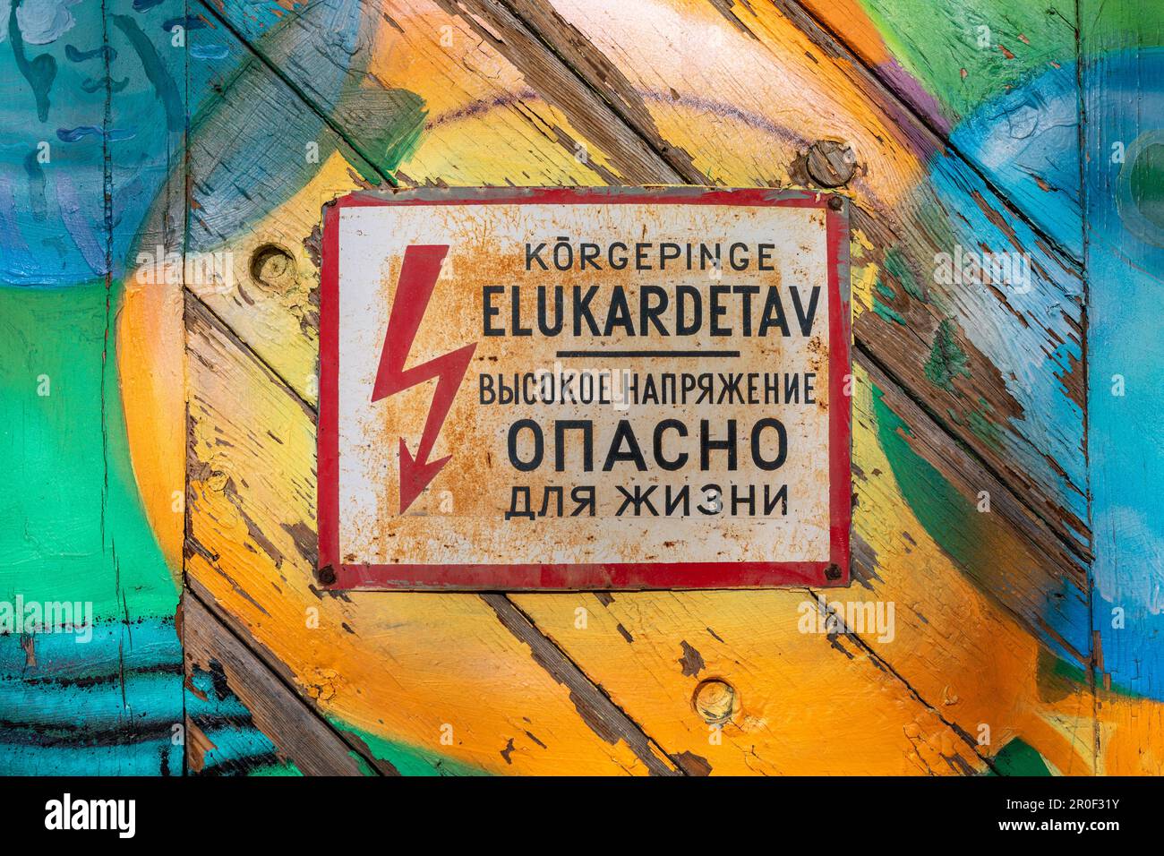Ancien signe d'avertissement de l'ère soviétique de l'électricité haute tension sur une porte en bois colorée dans le quartier Telliskivi de Tallinn, Estonie Banque D'Images Ancien signe d'avertissement de l'ère soviétique de l'électricité haute tension sur une porte en bois colorée dans le quartier Telliskivi de Tallinn, Estonie Banque D'Images