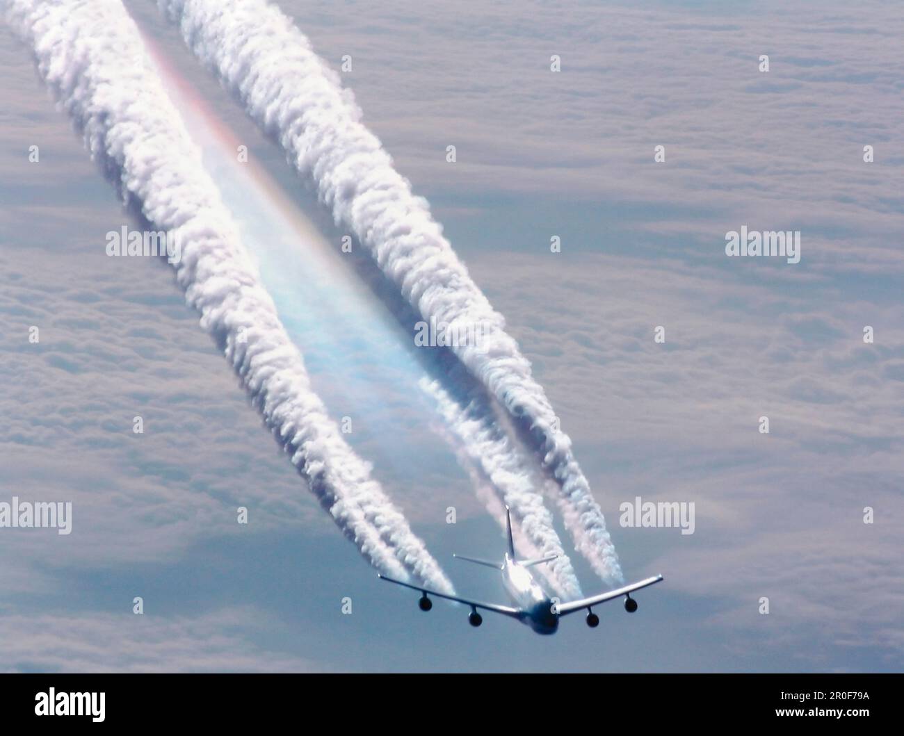 Avion survolant la mer de nuages laissant d'énormes sentiers de condensation Banque D'Images