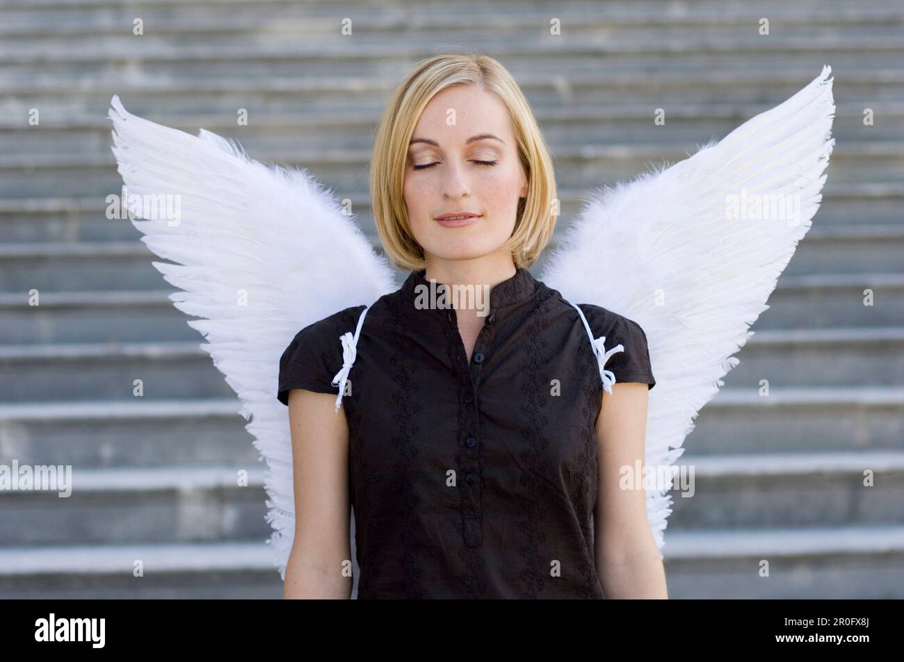 Femme adulte de taille moyenne portant des ailes d'ange avec des yeux fermés Banque D'Images