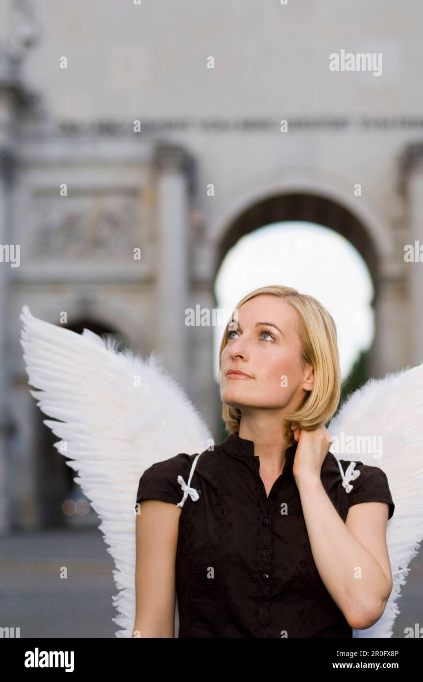Femme adulte de taille moyenne portant des ailes d'ange près de la porte de la victoire, Munich, Bavière, Allemagne Banque D'Images