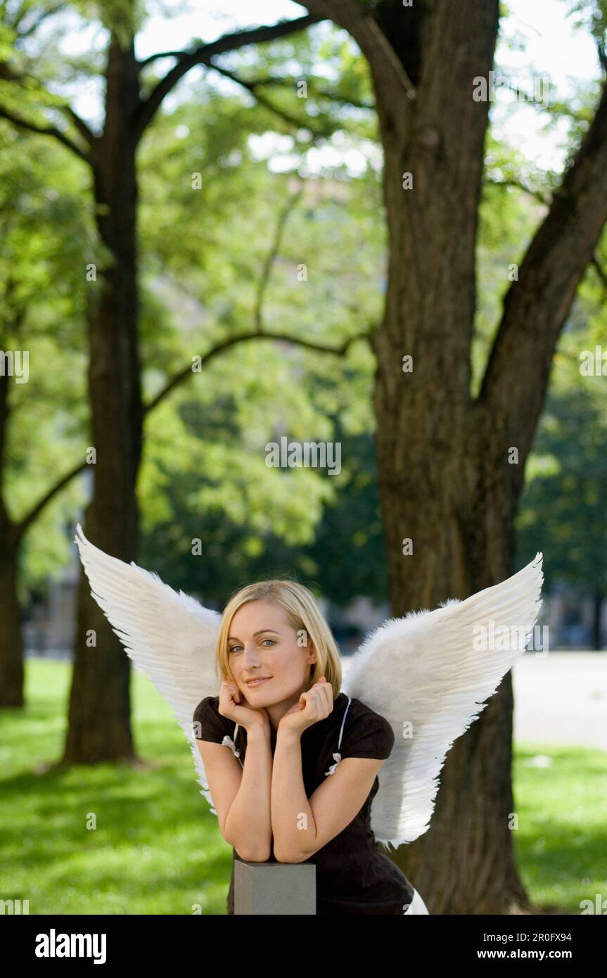 Femme adulte de taille moyenne portant des ailes d'ange dans un parc Banque D'Images