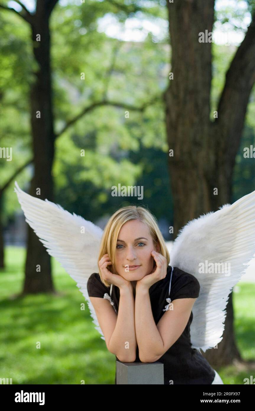 Femme adulte de taille moyenne portant des ailes d'ange dans un parc Banque D'Images