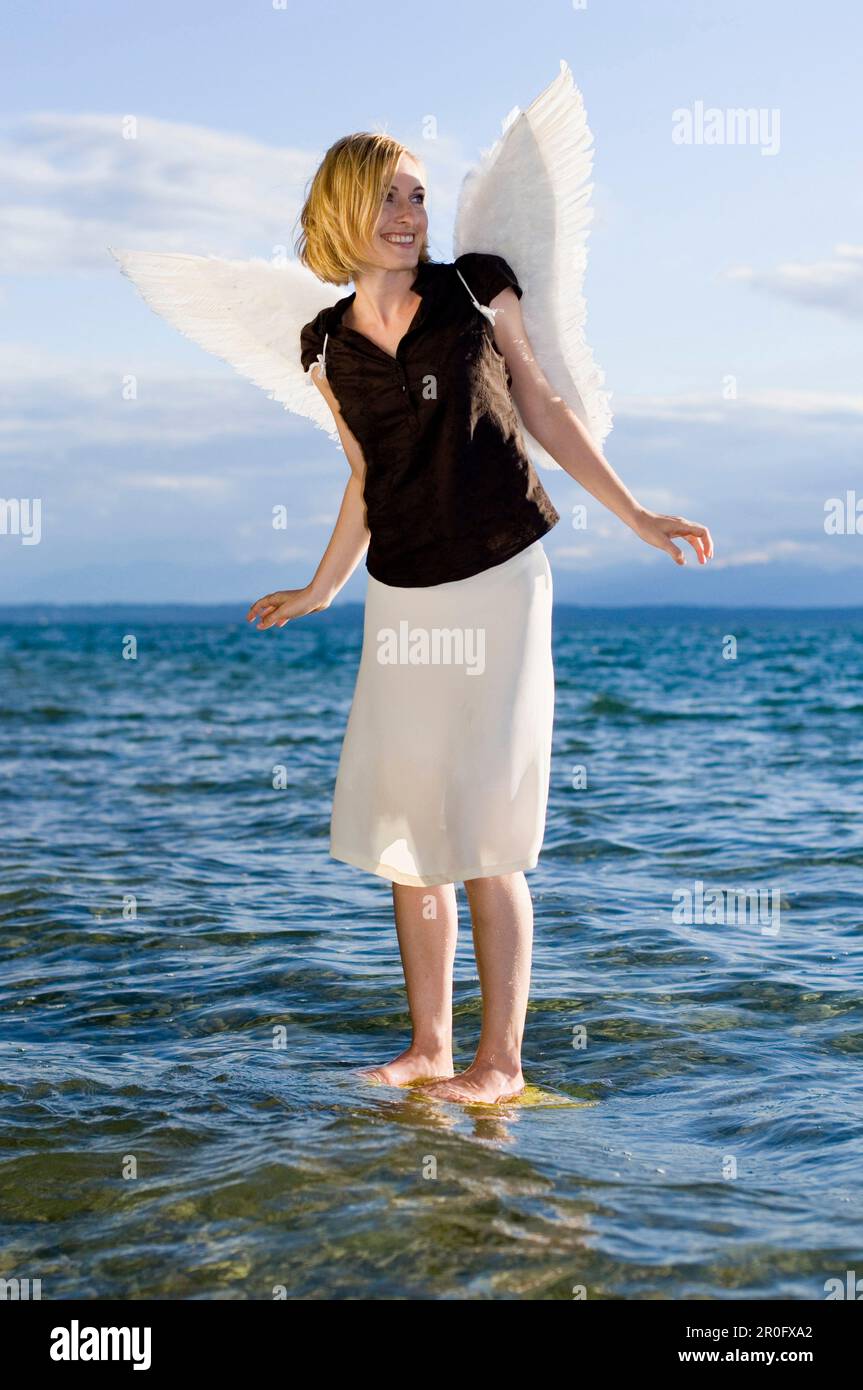 Femme adulte de taille moyenne portant des ailes d'ange debout dans le lac Starnberg, Bavière, Allemagne Banque D'Images