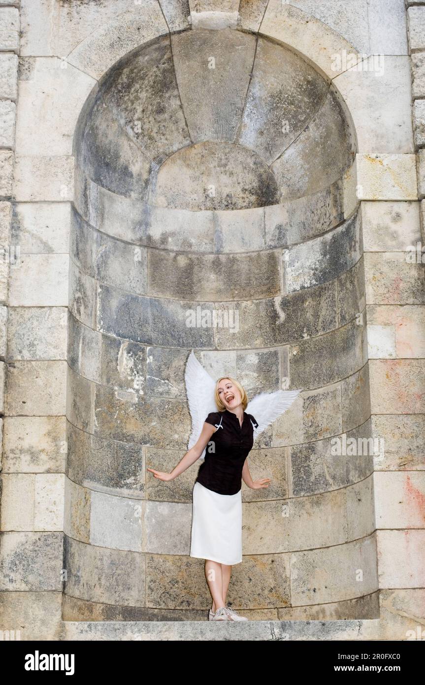 Femme adulte de taille moyenne portant des ailes d'ange debout dans une alcôve, Munich, Bavière, Allemagne Banque D'Images