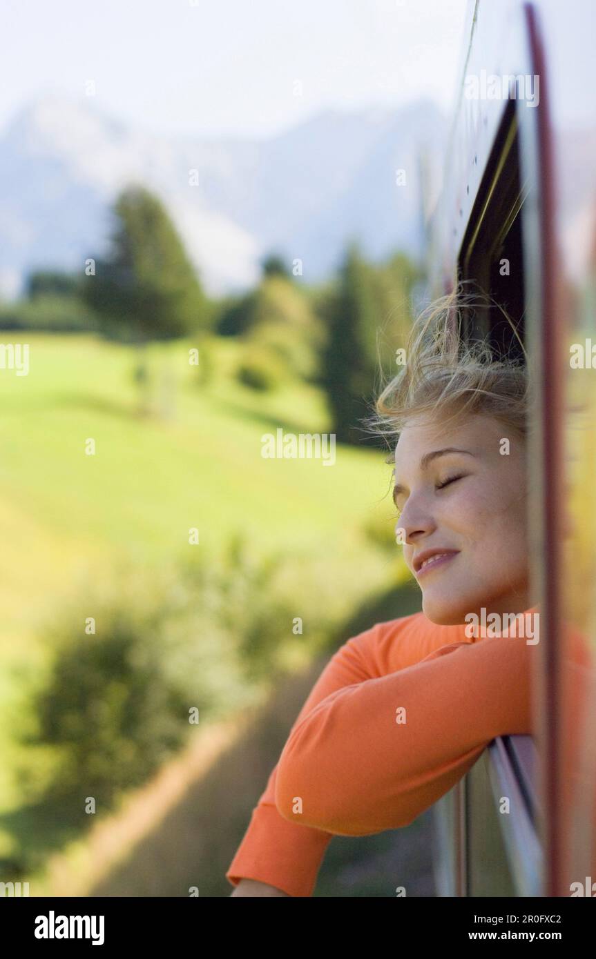 Jeune femme aux yeux fermés penchée par une fenêtre de train rapide Banque D'Images