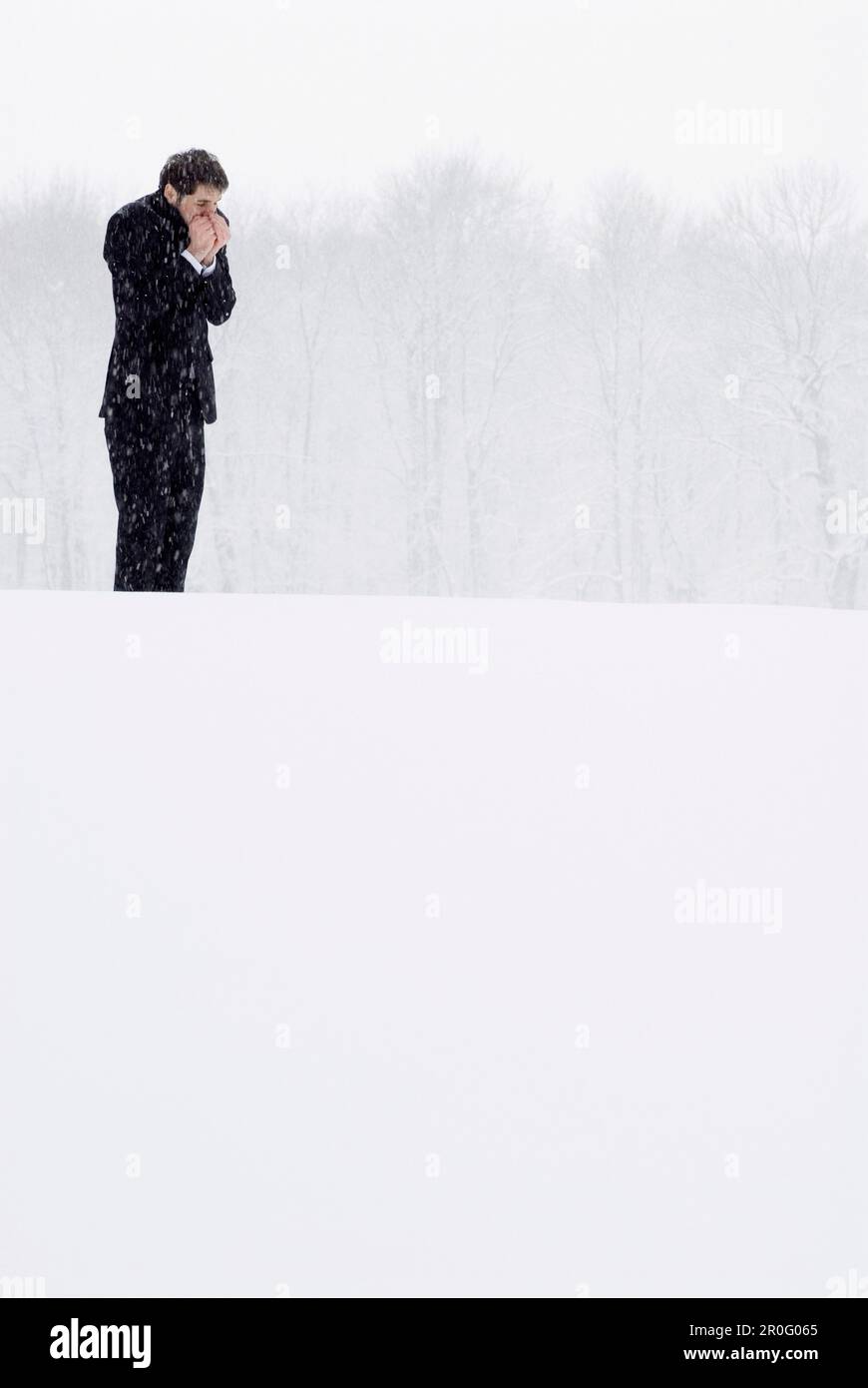 Homme d'affaires debout dans une effervescence enneigée réchauffant ses mains, jardin anglais, Munich, Bavière, Allemagne Banque D'Images