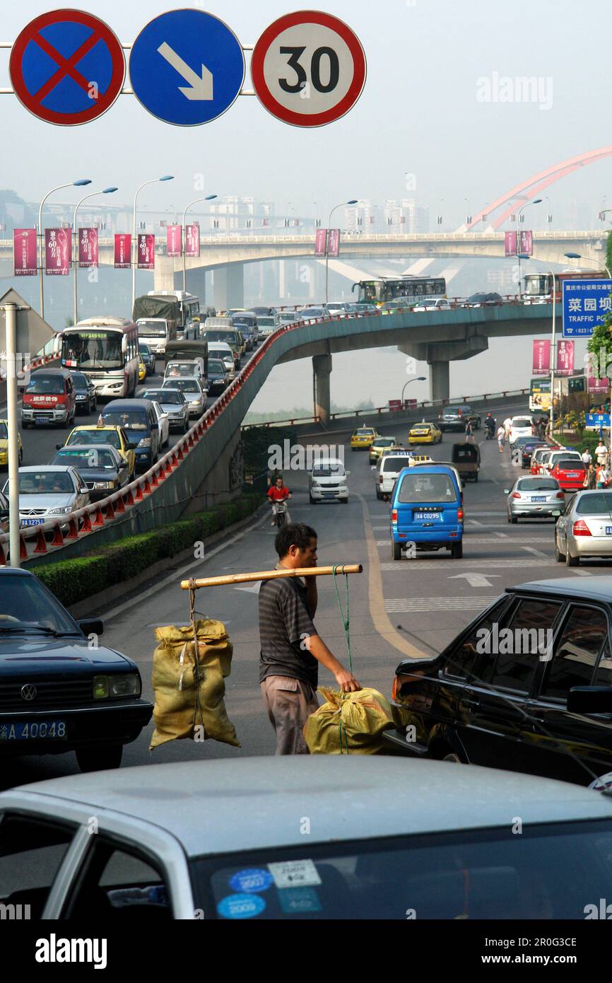 L'homme porte une lecture lourde à travers le rushhhour des rues de Chongqing, Chine, Asie Banque D'Images