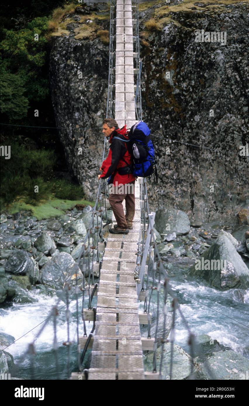 L'homme sur un pont suspendu au-dessus de la rivière Dart Rees, Mount Aspiring National Park, Île du Sud, Nouvelle-Zélande, Océanie Banque D'Images