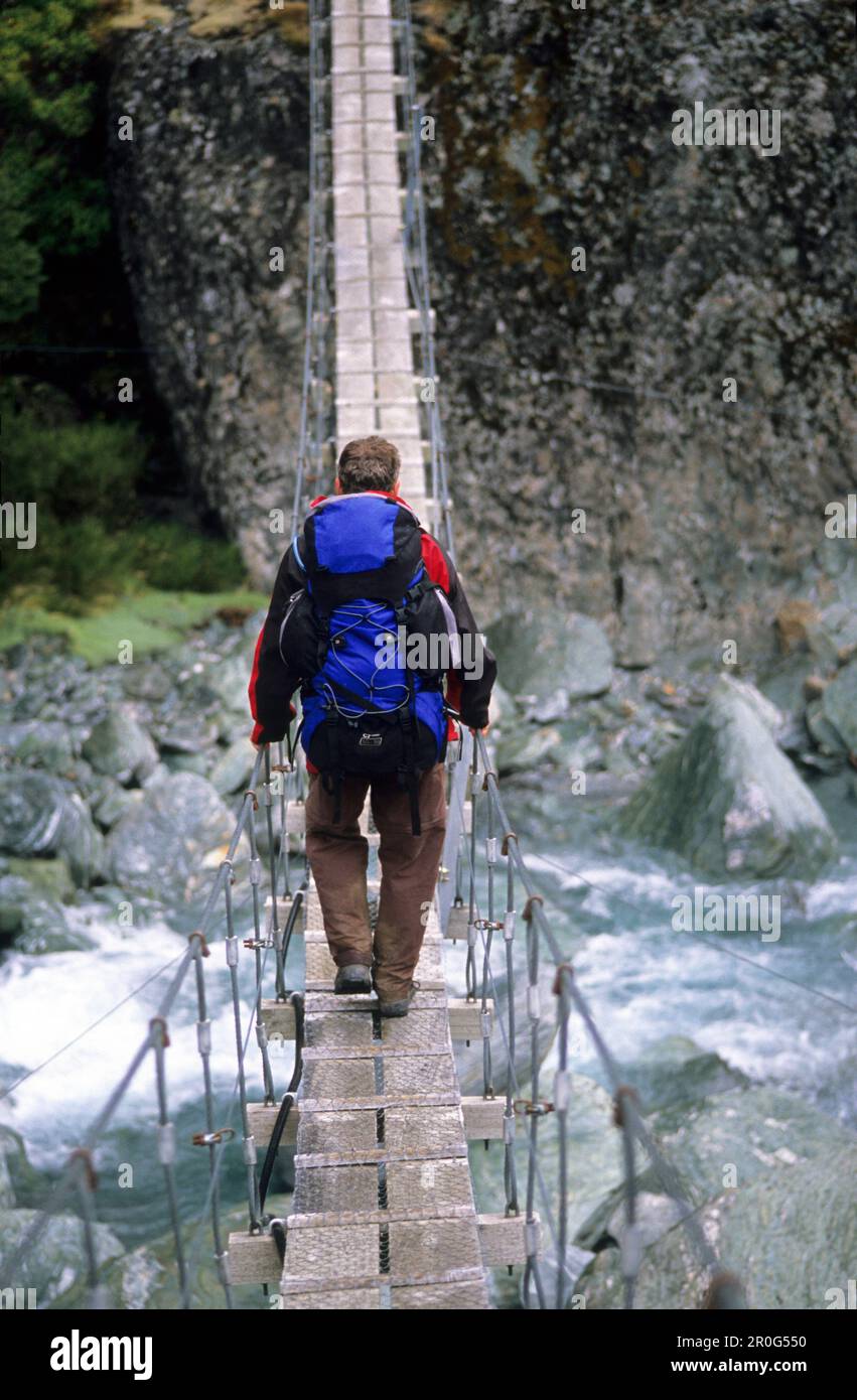 L'homme sur un pont suspendu au-dessus de la rivière Dart Rees, Mount Aspiring National Park, Île du Sud, Nouvelle-Zélande, Océanie Banque D'Images