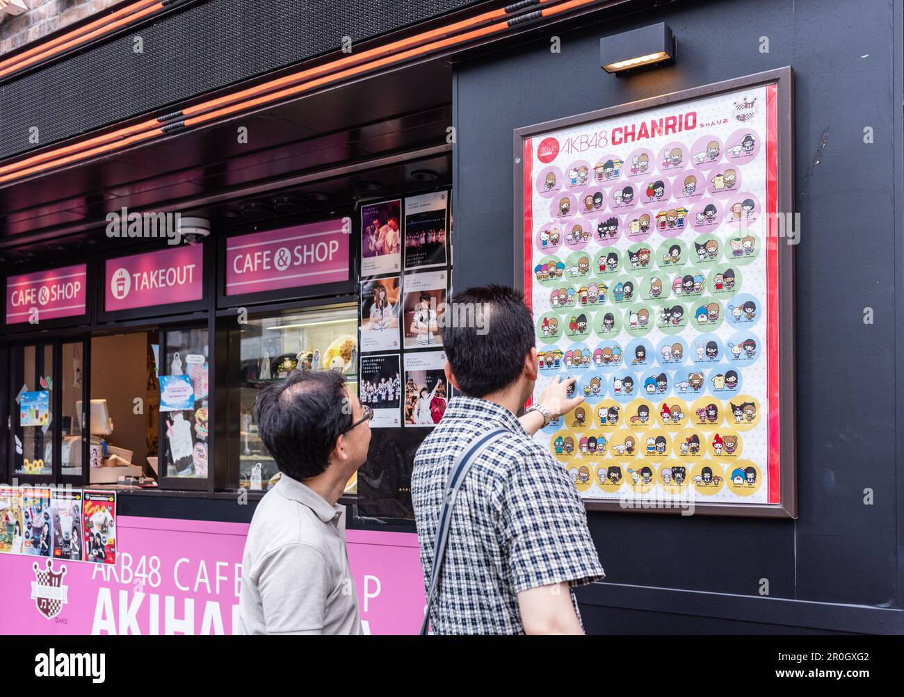 Deux hommes sélectionnent des personnages animés au Tokyo café. Banque D'Images