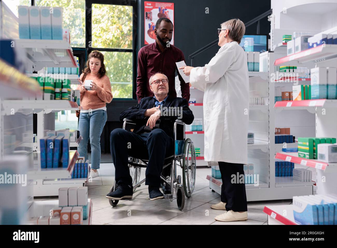 Aide-soignant aidant un client senior en fauteuil roulant avec des achats  de soins de santé en pharmacie, offrant une ordonnance médicale au  pharmacien demandant de l'aide avec des pilules. Service et support