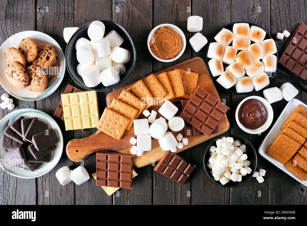 Table de buffet Smores. Marshmallows rôtis, craquelins, chocolat et une variété d'ingrédients. Vue en hauteur sur fond de bois sombre. Banque D'Images