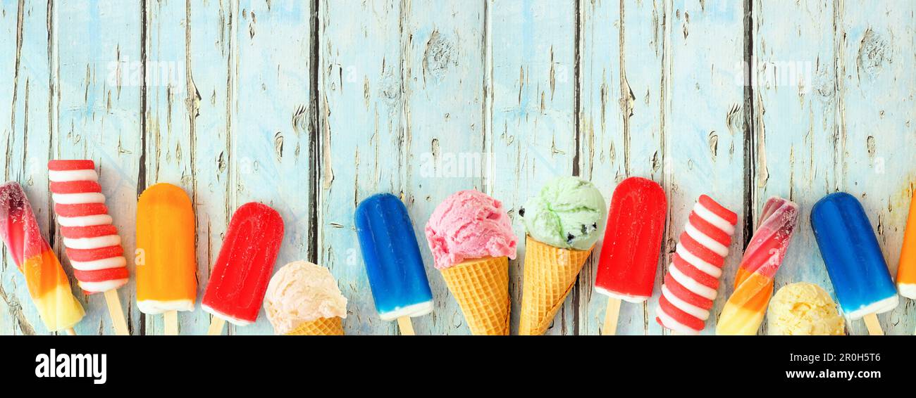 Variété de popsicles d'été colorés et de crèmes glacées. Vue du haut bordure inférieure sur un arrière-plan rustique de bannière en bois bleu. Copier l'espace. Banque D'Images