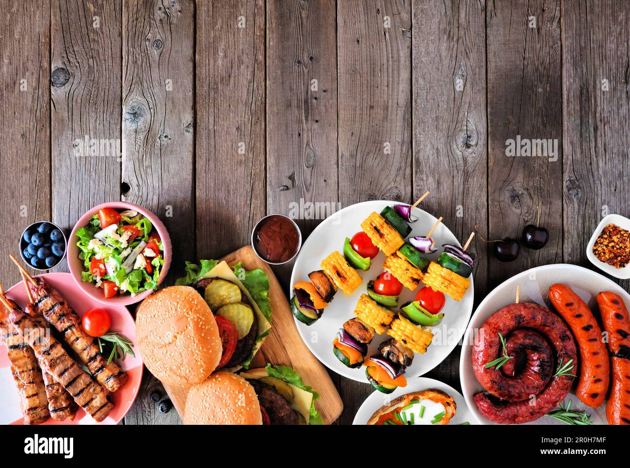Barbecue d'été ou pique-nique bordure inférieure. Collection de hamburgers, viande grillée, légumes, fruits, salade et pommes de terre. Vue de haut en bas sur un bac en bois sombre Banque D'Images