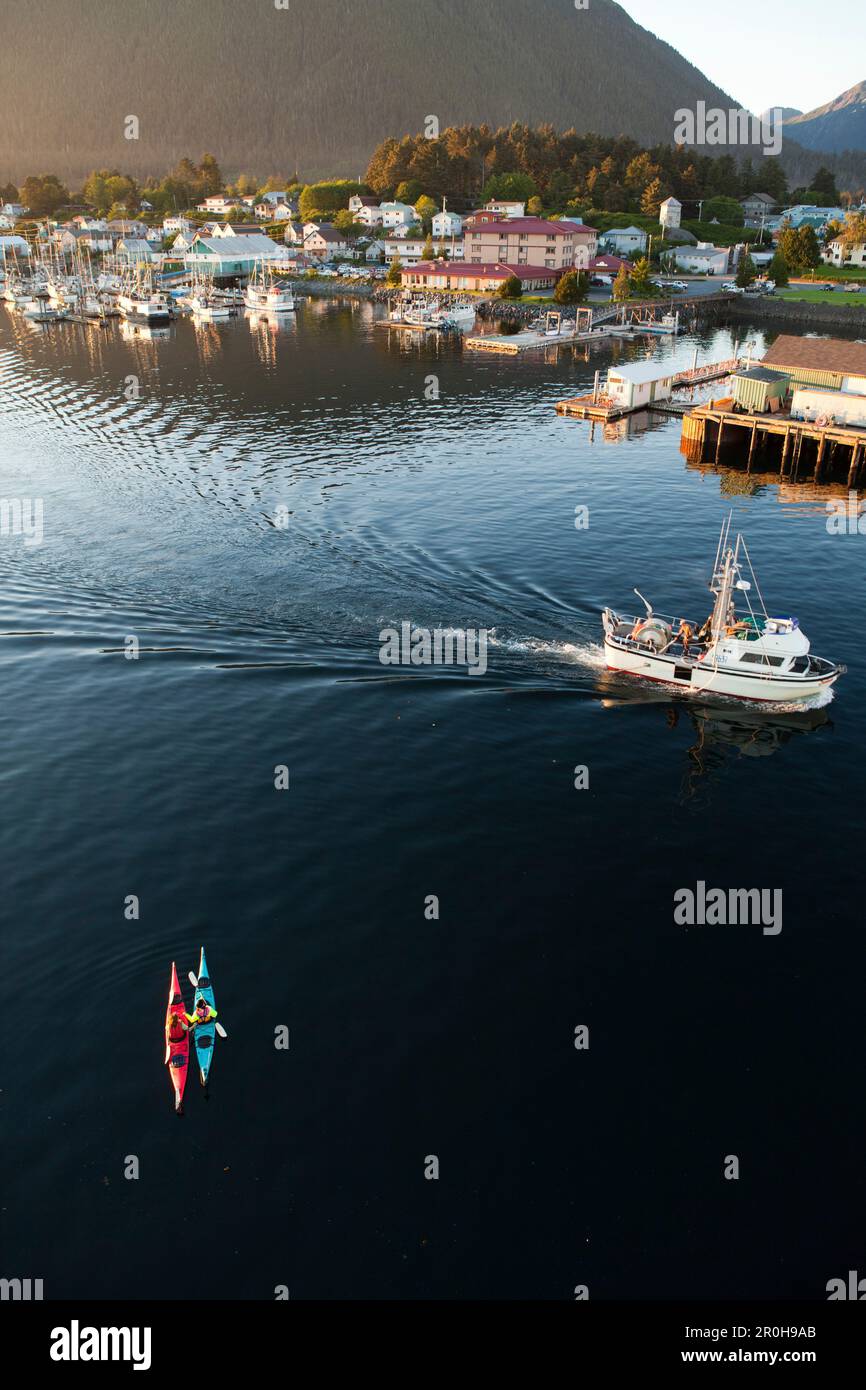 ALASKA, Sitka, les kayakistes se reposent dans le port de Sitka pendant qu'un bateau de pêche passe Banque D'Images