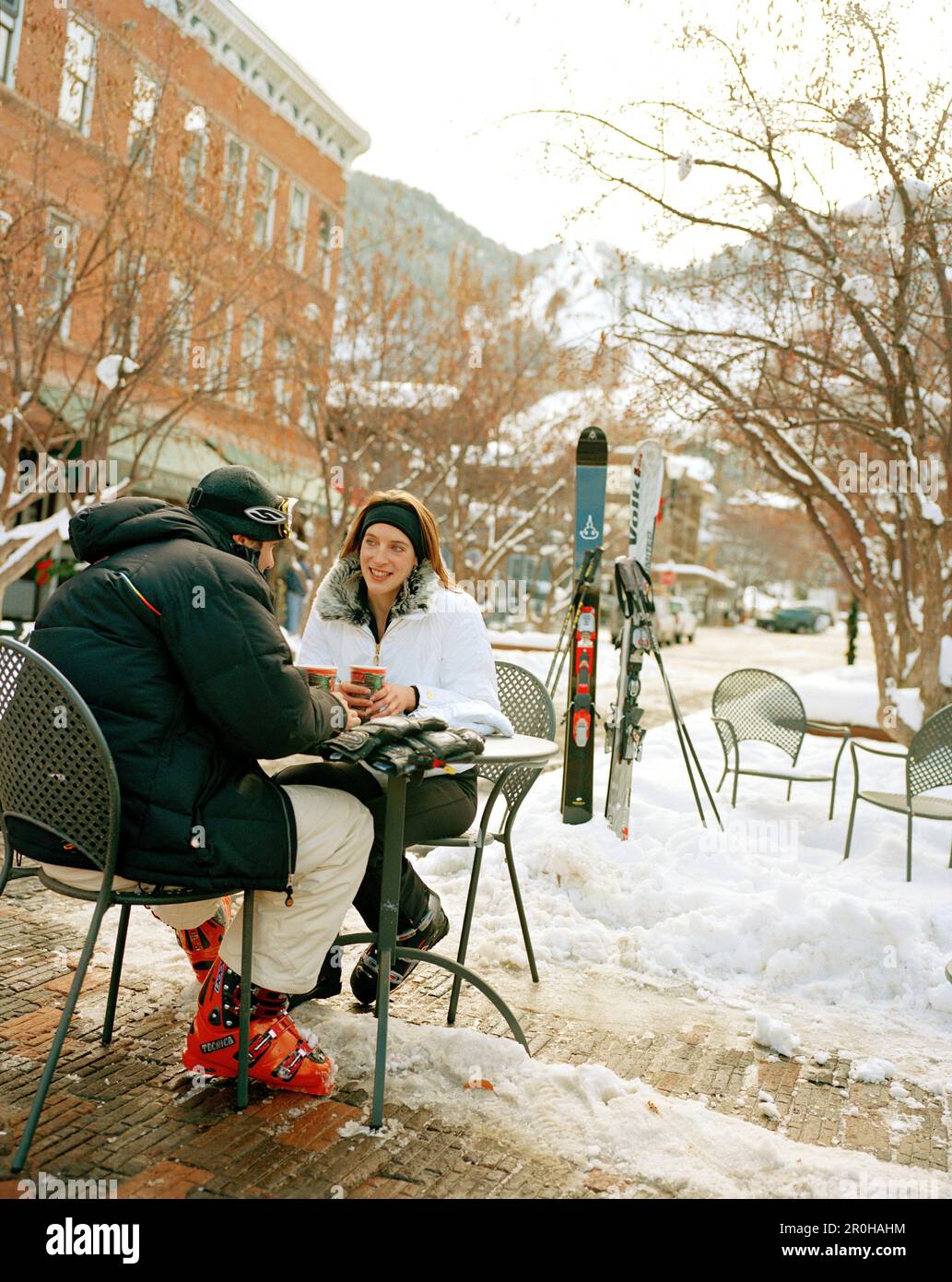 États-Unis, Colorado, Aspen, couple portant des équipements de ski ayant un café à une table extérieure en hiver, au centre-ville Banque D'Images