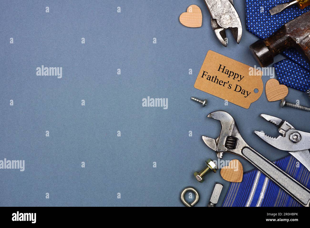 Étiquette cadeau Happy Pères Day avec bordure latérale de liens et d'outils sur fond de papier gris bleu. Vue de dessus avec espace de copie. Banque D'Images