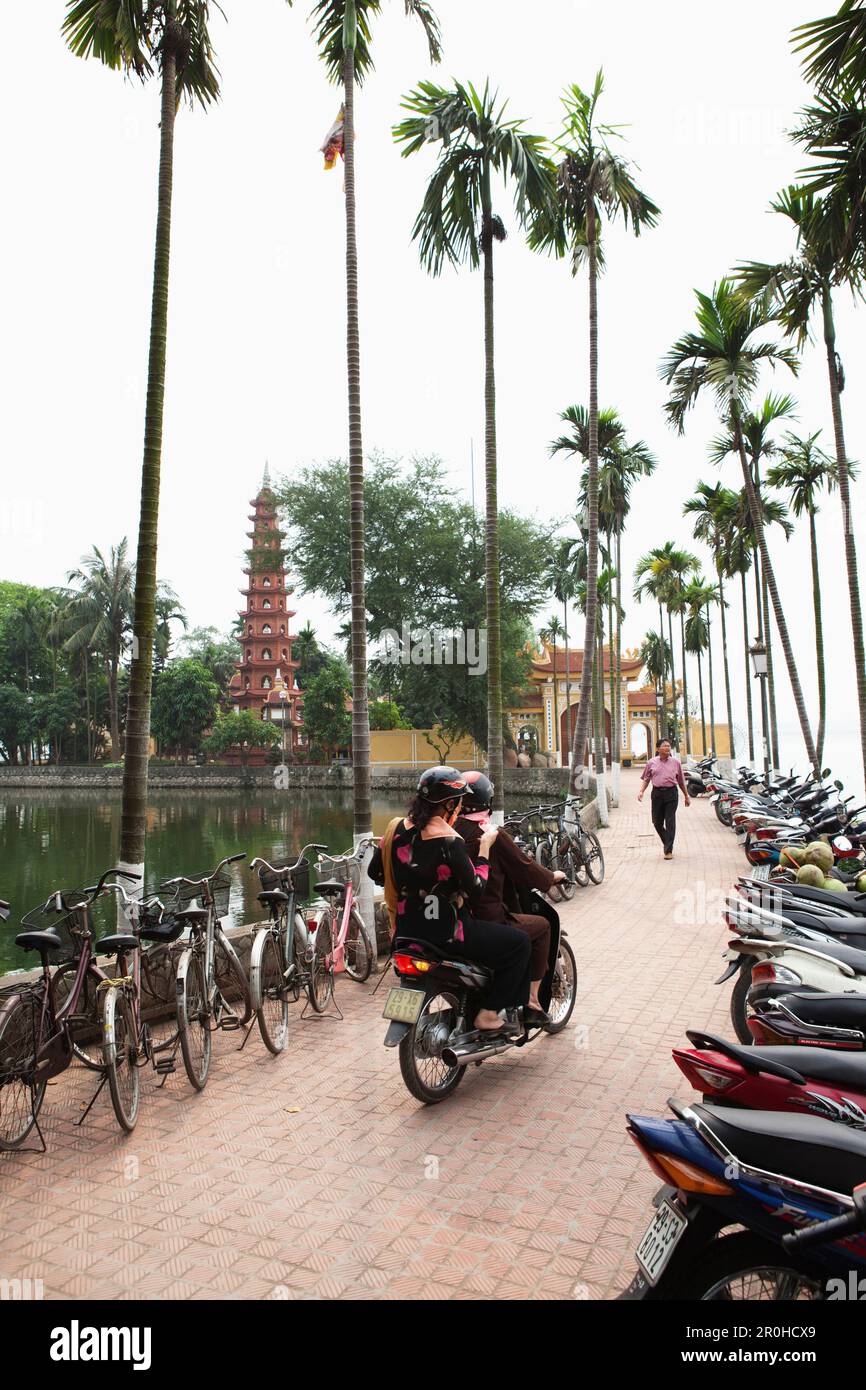 VIETNAM, Hanoi, deux personnes sur un cyclomoteur chercher une place de stationnement, la Pagode Tran Quoc Banque D'Images