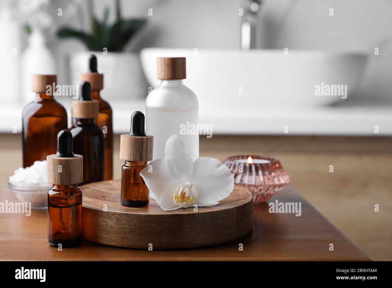 Huiles essentielles, fleurs d'orchidées et sel de mer sur une table en bois dans la salle de bains Banque D'Images