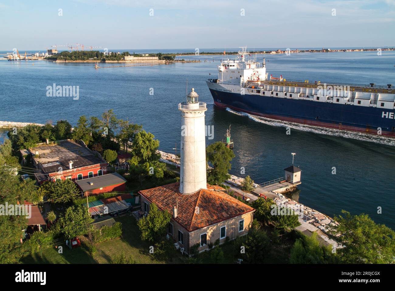 Le cargo passe le vieux phare d'Alberoni et la station pilote à la sortie Malamocco, fin du Lido, lagune, Lido, fond est MOSE, Venise, A Banque D'Images