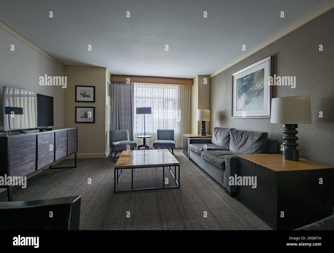 Suite affaires vide avec tv à écran plat, canapé, table en bois, tabourets de bar Banque D'Images