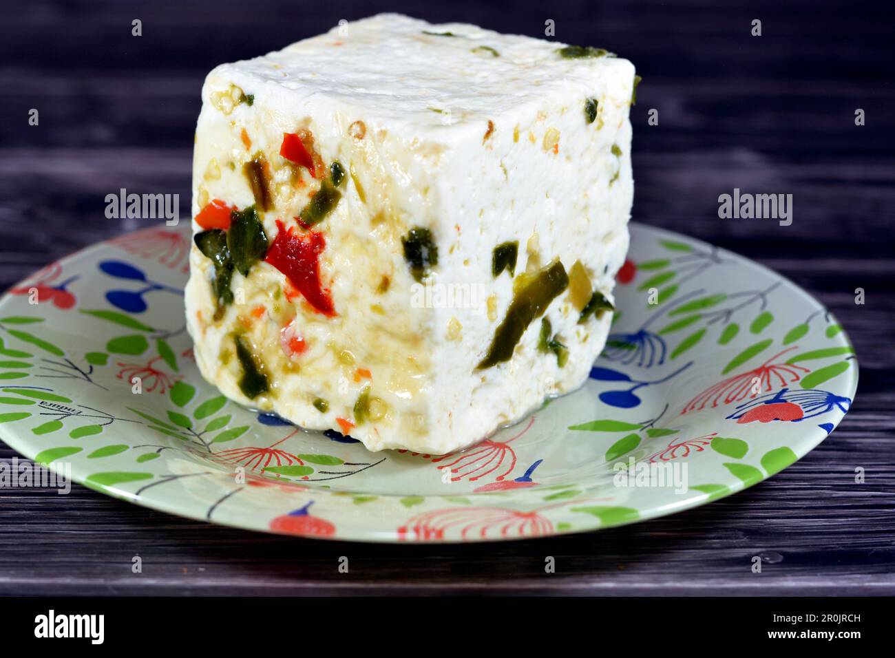 Assiette avec un cube de baril égyptien de fromage blanc de baramuli avec des tranches de poivrons rouges et verts, un fromage traditionnel du Moyen-Orient fait de table Banque D'Images