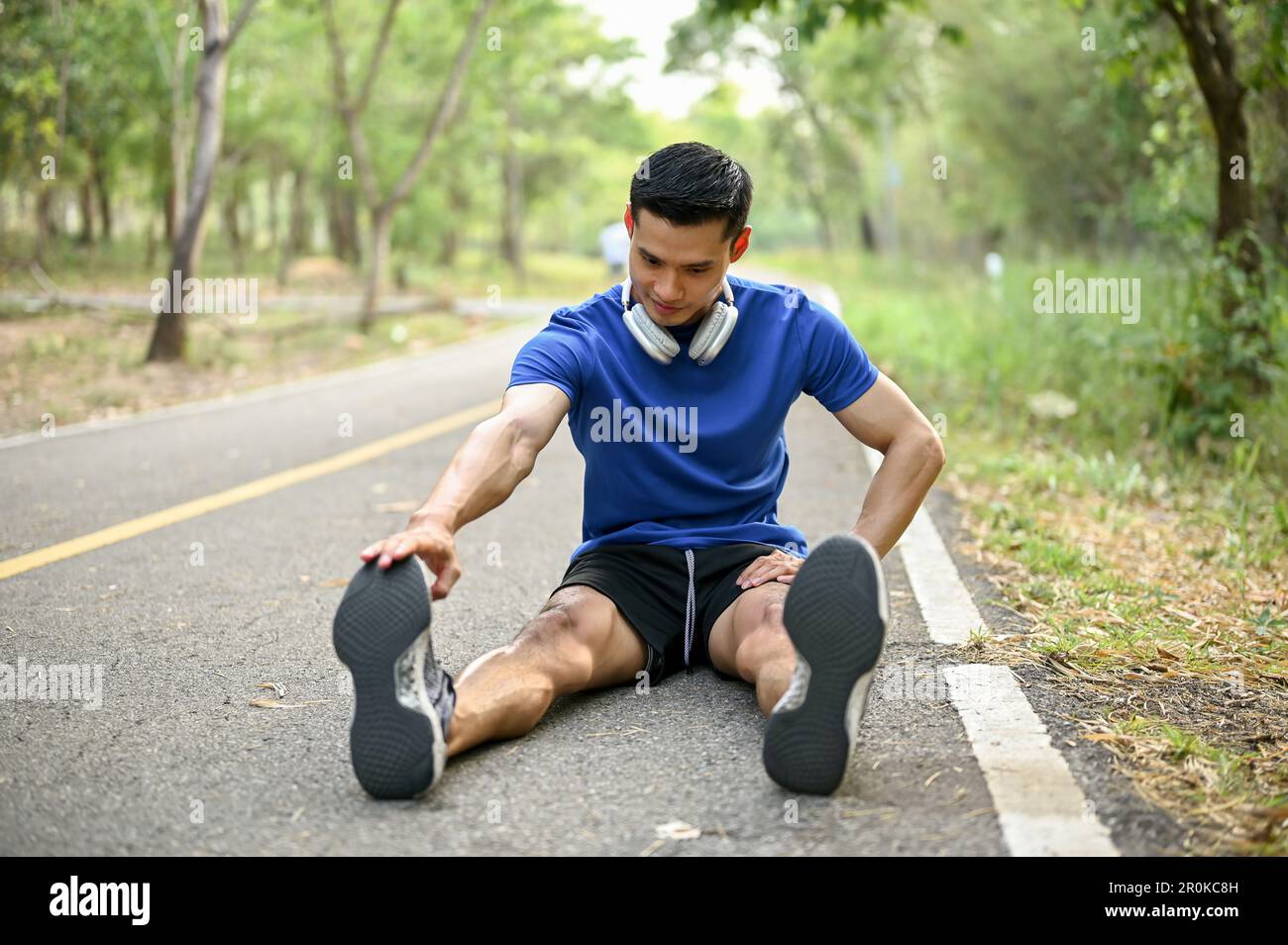 Beau homme asiatique millénaire qui s'étire les jambes dans la rue,  s'échauffe avant de courir dans un parc naturel. Concept de style de vie et  de sport Photo Stock - Alamy