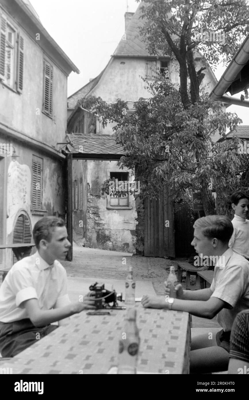 Junge Männer im Innenhof eines Weinlokals in der Drosselgasse in Rüdesheim, 1961. Jeunes hommes dans la cour d'un bar à vins dans la Drosselgasse à Rüdesheim, 1961. Banque D'Images