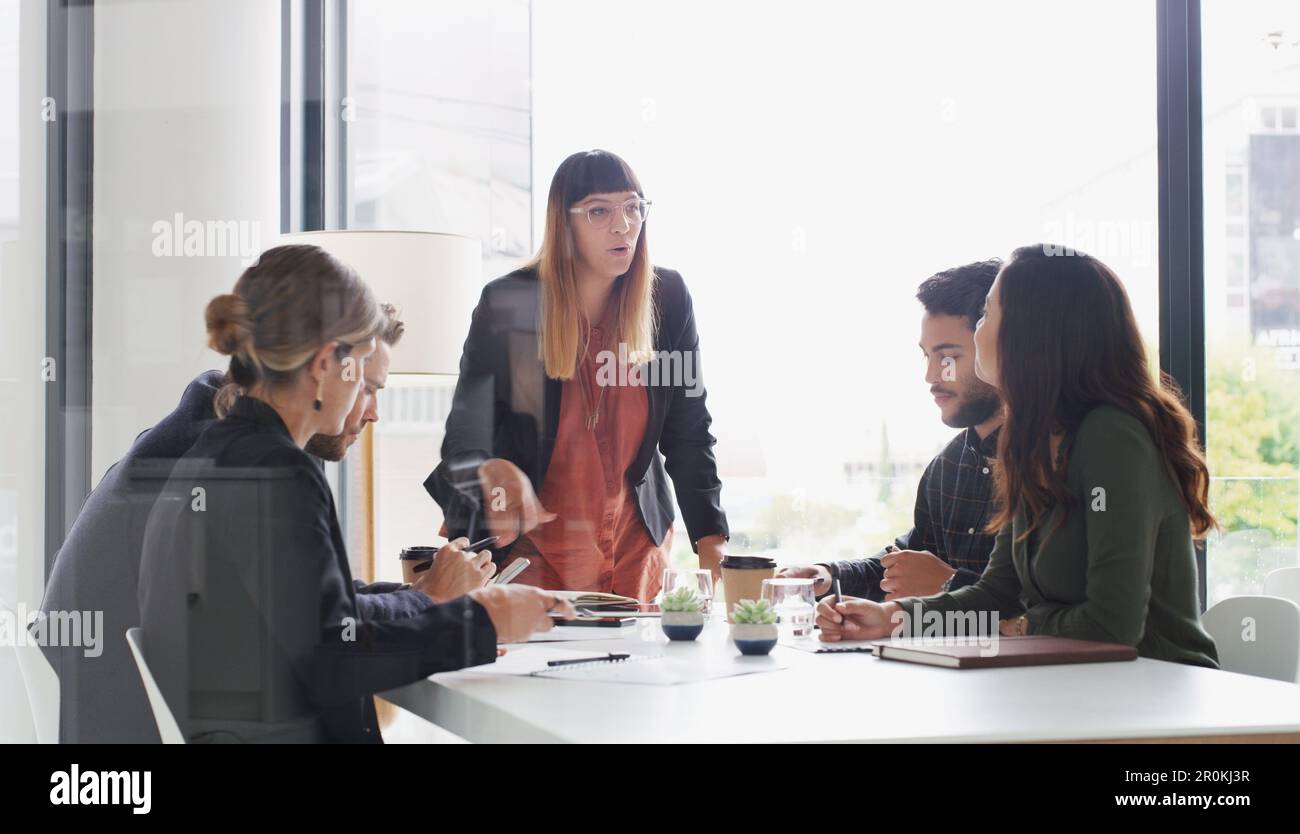 Regardons de plus près notre grand plan... une jeune femme d'affaires qui donne une présentation à ses collègues dans un bureau. Banque D'Images