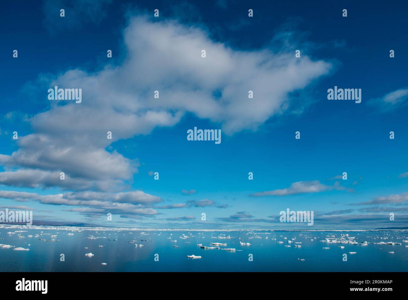 Les eaux calmes sont parsemées de morceaux de glace de mer sous un ciel bleu partiellement nuageux, vu à bord du bateau de croisière d'expédition MS Bremen (Hapag-Lloyd Cruises), Banque D'Images